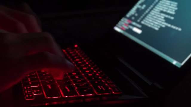 Hacker Typing Code on Laptop