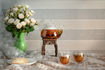 Chinese tea set combine of clear glass chinese tea pot and two tea cups with vase of white roses
