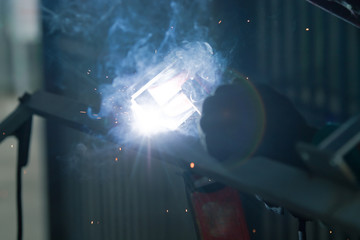 welder is welding metal part with lots of sparks