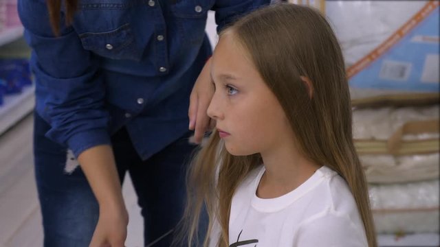 Hairdresser making hairdo for adorable girl in beauty salon
