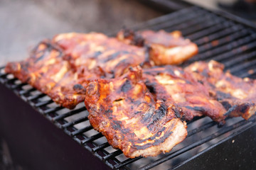 Beef ribs on grill grate in open air. Roasted meat on the fire. Traditional meat cooking.