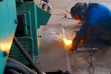 The welder at the industrial plant makes the connection using an electric arc.