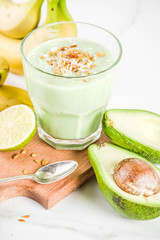 Healthy summer drink, avocado and banana smoothie with lime, granola and coconut milk, dark rusty background copy space