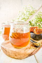 Organic floral honey, in jars, with pollen and honey combs, on a white wooden table, with wildflowers, copy space