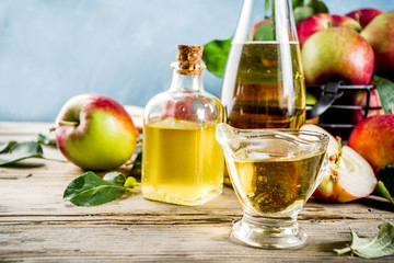 Homemade apple cider vinegar with fresh apples om wooden rustic background copy space
