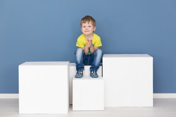happy childhood - little cheerful boy posing by the blue wall
