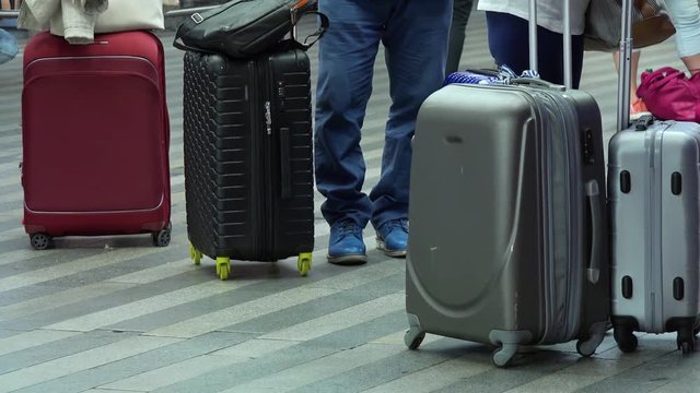 Closeup on the suitcases of the people in a train station building