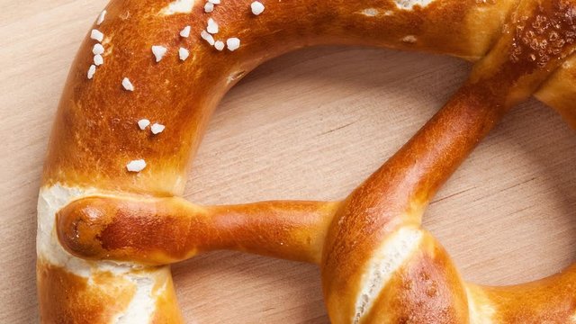 Rotating over baked Bavarian pretzel on wooden background