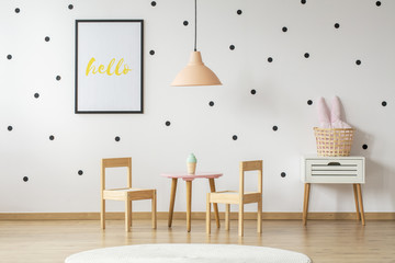 Scandinavian style nightstand and a wooden toy dining set in a cute, girly bedroom interior for a child with white wall and pastel pink decorations