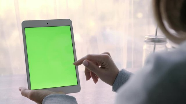 Close-up of a woman's hands working on green screen on a tablet pc.