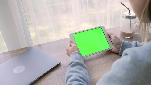 Close-up of a woman's hands working on green screen on a tablet pc