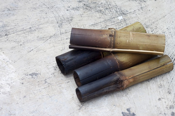 Glutinous rice roasted in bamboo joints put on cement floor.