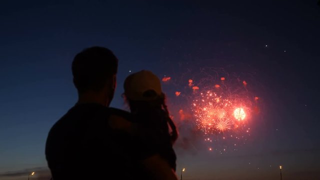 Happy father and daughter watching colorful fireworks.