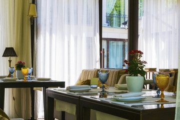 Modern european restaurant with wooden table and multi-colored sofa close to window.