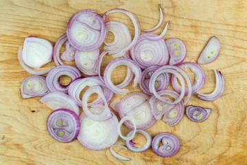 Sliced red onion rings on wooden background top view