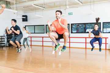 Clients Doing Tuck Jumps On Hardwood Floor In Gym - obrazy, fototapety, plakaty