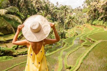 Beautiful young lady in shine through dress touch straw hat. Girl walk at typical Asian hillside...
