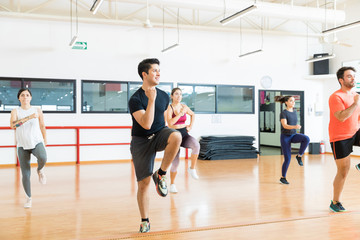 Fototapeta premium Man With Friends Performing High Knee Running In Aerobics Class