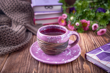 Autumn composition. Fruit tea, books, knitted sweater and flowers asters on a wooden background. Free space
