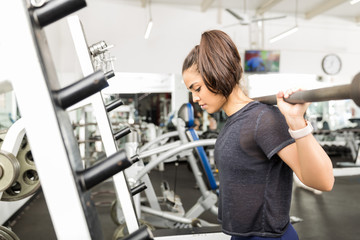 Fototapeta premium Woman Exercising With Empty Barbell During Gym Class