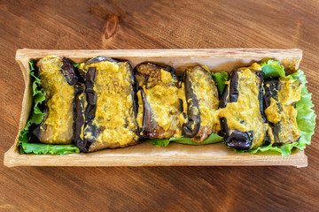 Fried aubergines with nut filling in a bowl of bamboo trunk. Aubergines in Georgian.