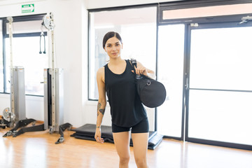 Sporty Young Woman With Duffle Bag Standing In Gym