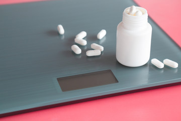 White pills with bottle on the weight scale. Nutritional supplements. Receiving vitamins. Daily...