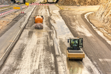 Steamroller doing road construction workPreparation of surface with water tank truck for asphalted