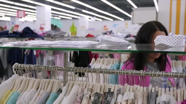 Beautiful woman shopping clothes on hangers in boutique