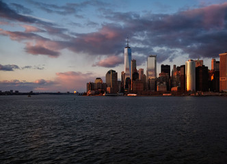 Obraz premium New York City skyline with urban skyscrapers over Hudson River at sunset. Manhattan downtown panorama. Waterfront view to the harbor at twilight.