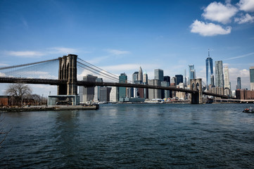 Fototapeta na wymiar Brooklyn bridge with New York City skyline panoramic spring view. Lower Manhattan downtown scenery from Brooklyn Bridge Park riverbank in Dumbo district, NYC, USA.