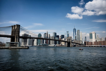 Fototapeta premium Most Brookliński z panoramicznym widokiem na Nowy Jork. Sceneria centrum dolnego Manhattanu z brzegu rzeki Brooklyn Bridge Park w dzielnicy Dumbo, Nowy Jork, USA.