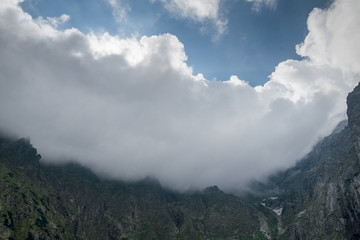 Scenic view of beautiful rocky mountain peaks covered by clouds. Marine Eye lake, High Tatras, Zakopane, Poland. Foggy day
