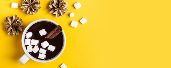 Warme chocolademelk beker met kaneel en marshmallow op gele achtergrond. Verwarmende kerst winterdrank