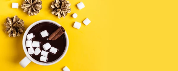 Keuken foto achterwand Chocolade Warme chocolademelk beker met kaneel en marshmallow op gele achtergrond. Verwarmende kerst winterdrank