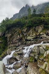 Scenic view of the waterfall on the rocky mountains near the Morskie Oko lake, High Tatras, Zakopane, Poland. Foggy day
