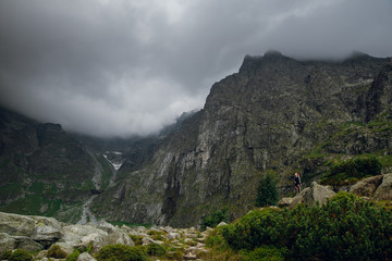 Scenic view of beautiful rocky mountains and peaks covered by clouds. Marine Eye lake, High Tatras, Zakopane, Poland. Dark foggy day