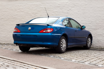 Fototapeta na wymiar Blue dynamic sports car parked in front of a gray wall