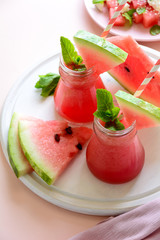 Summer watermelon smoothie decorated mint leaves and watermelon salad with feta cheese on pink background. Summer drink and healthy eating concept
