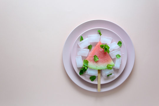 Frozen watermelon popsicles – homemade ice cream with mint on pink plate. Top view