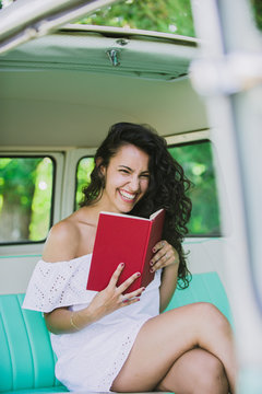 Woman sitting inside a caravan and reading a book