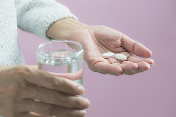 Taking medicine pills. Woman holds in hands the medicine pills and a glass of water.  Healthcare concept.