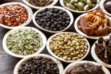 Group of indian spices in coconut bowls on wooden background