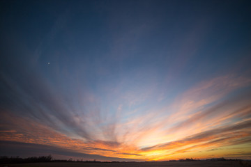 Partially Cloudy Dramatic Sunset Sky over Winter Fields and Meadows.
