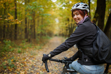 Obraz premium Photo of smiling brunette in helmet riding bicycle in autumn park