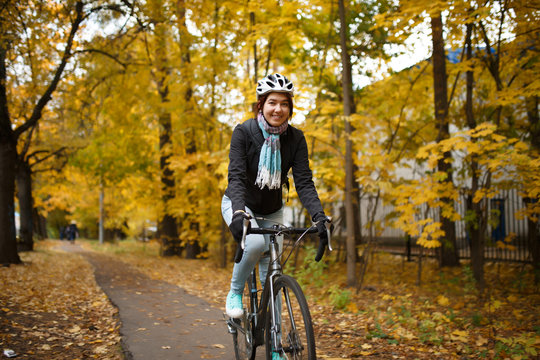 Photo of woman in helmet riding bicycle along path