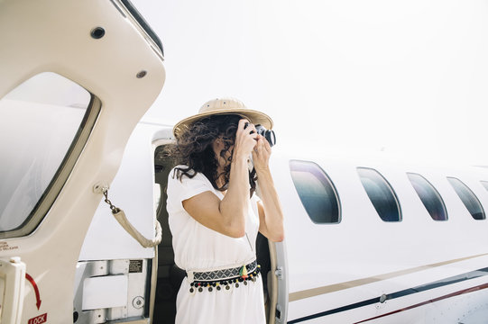 Pretty woman lowers an outdoor airplane and takes photos.