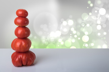 Recipe template. Ripe fresh red tomatoes stacked as a tower on a table with bright bokeh background. For your food and product display montage.