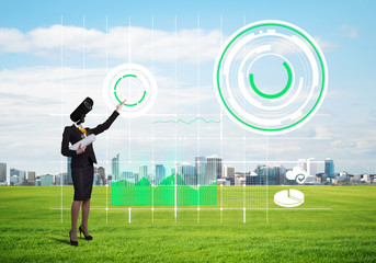 Camera headed woman standing on green grass against modern cityscape