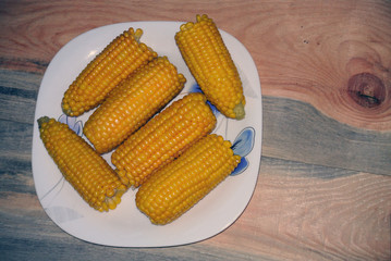 plate with boiled corn on a wooden background